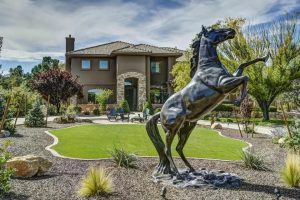 Elegant estate with a majestic horse statue in the foreground, highlighting luxury living with a touch of nature's grace and showcasing how to create a low water garden.