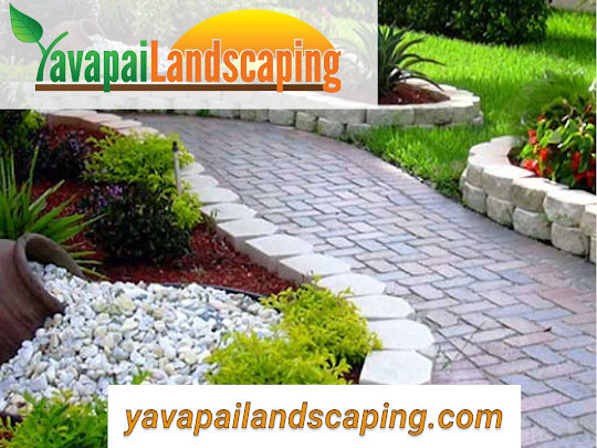 A neatly designed garden pathway with white stepping stones and curved retaining wall, surrounded by well-maintained greenery and decorative gravels, expertly avoiding common landscaping mistakes, with the logo and website for