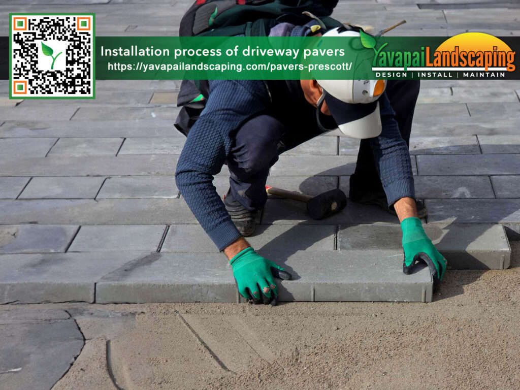 A worker meticulously installs driveway pavers, showcasing the detailed process of paving.