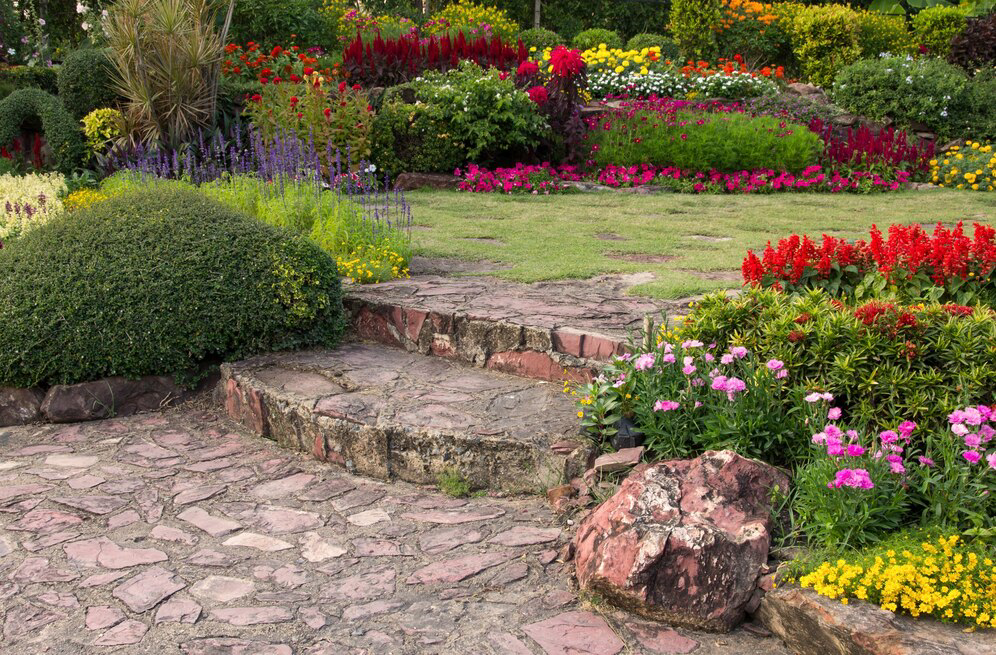 A tranquil garden path meanders through a vibrant array of colorful flowers and lush greenery, inviting a peaceful stroll amidst nature's beauty.