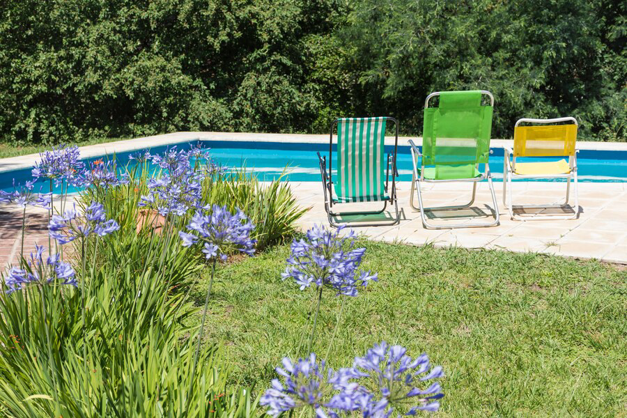 Relaxation awaits by the poolside, where colorful, space-maximizing chairs invite you to sit back amidst blooming flowers under the tranquil hug of the sun.