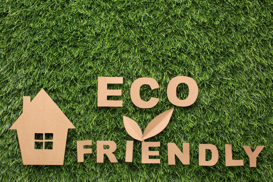 Cut-out cardboard pieces forming the words 'eco friendly' with a simple house shape on a lush green grass background, symbolizing eco-conscious living and sustainable housing to elevate your curb appeal.