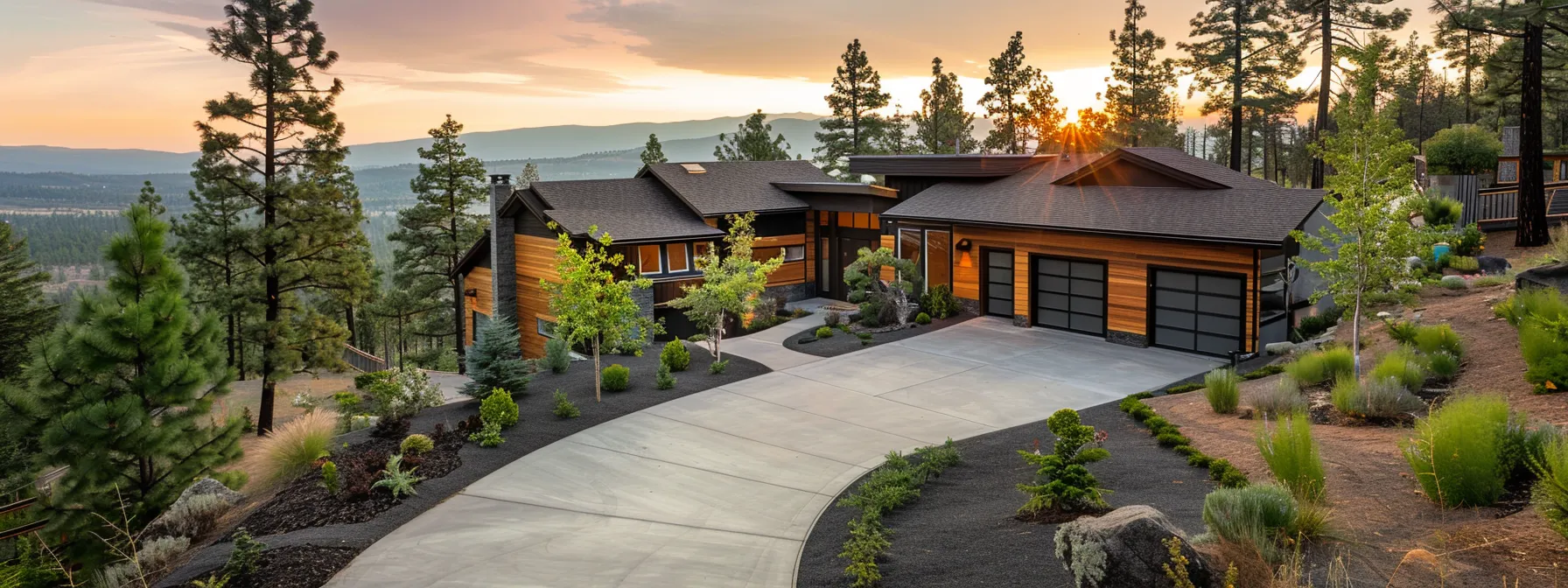 Modern home with firewise landscaping, surrounded by native plants and trees, emphasizing defensible space and fire safety in a natural setting.