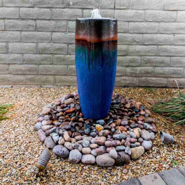 Water feature fountain with blue ceramic design, surrounded by smooth stones, enhancing outdoor landscaping in Prescott Valley.