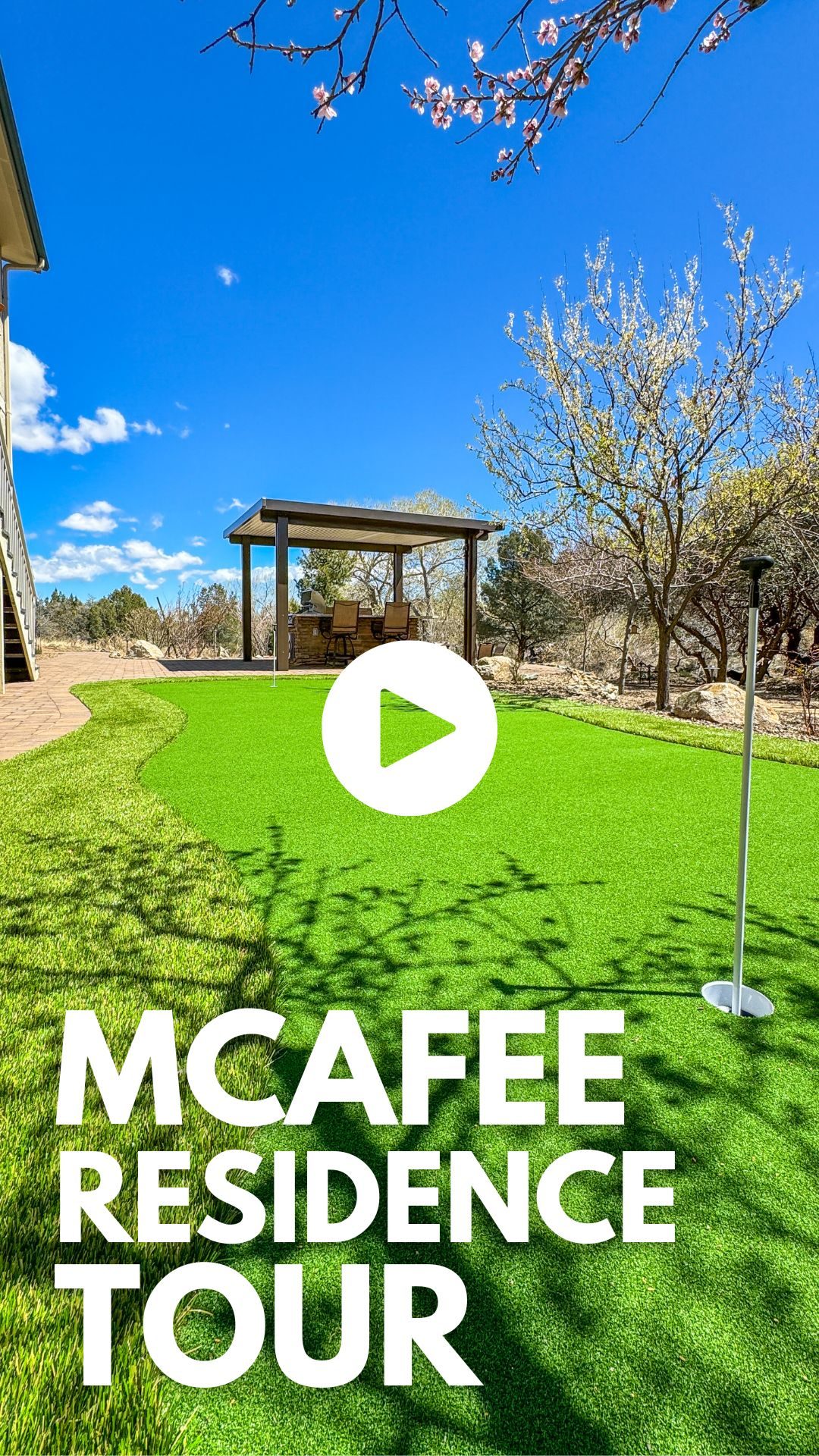 A backyard with a well-maintained artificial grass lawn and a putting green featuring a flagstick. In the background, there is a gazebo with seating under a clear blue sky. The text "RADIL RESIDENCE TOUR" is written at the bottom, with a play icon in the center.